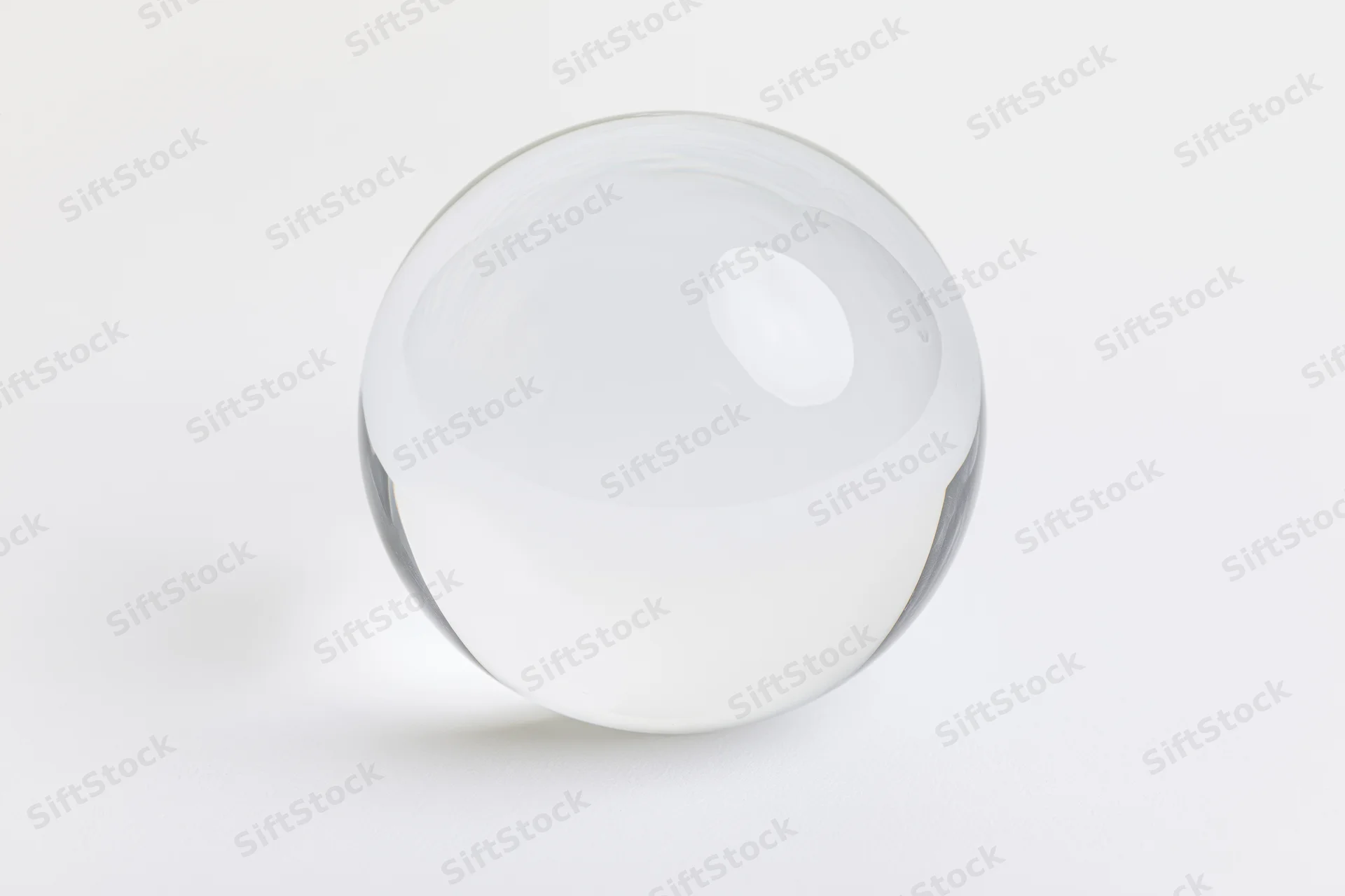 Clear glass sphere resting on plain white surface centered