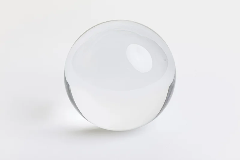 Clear glass sphere resting on plain white surface centered