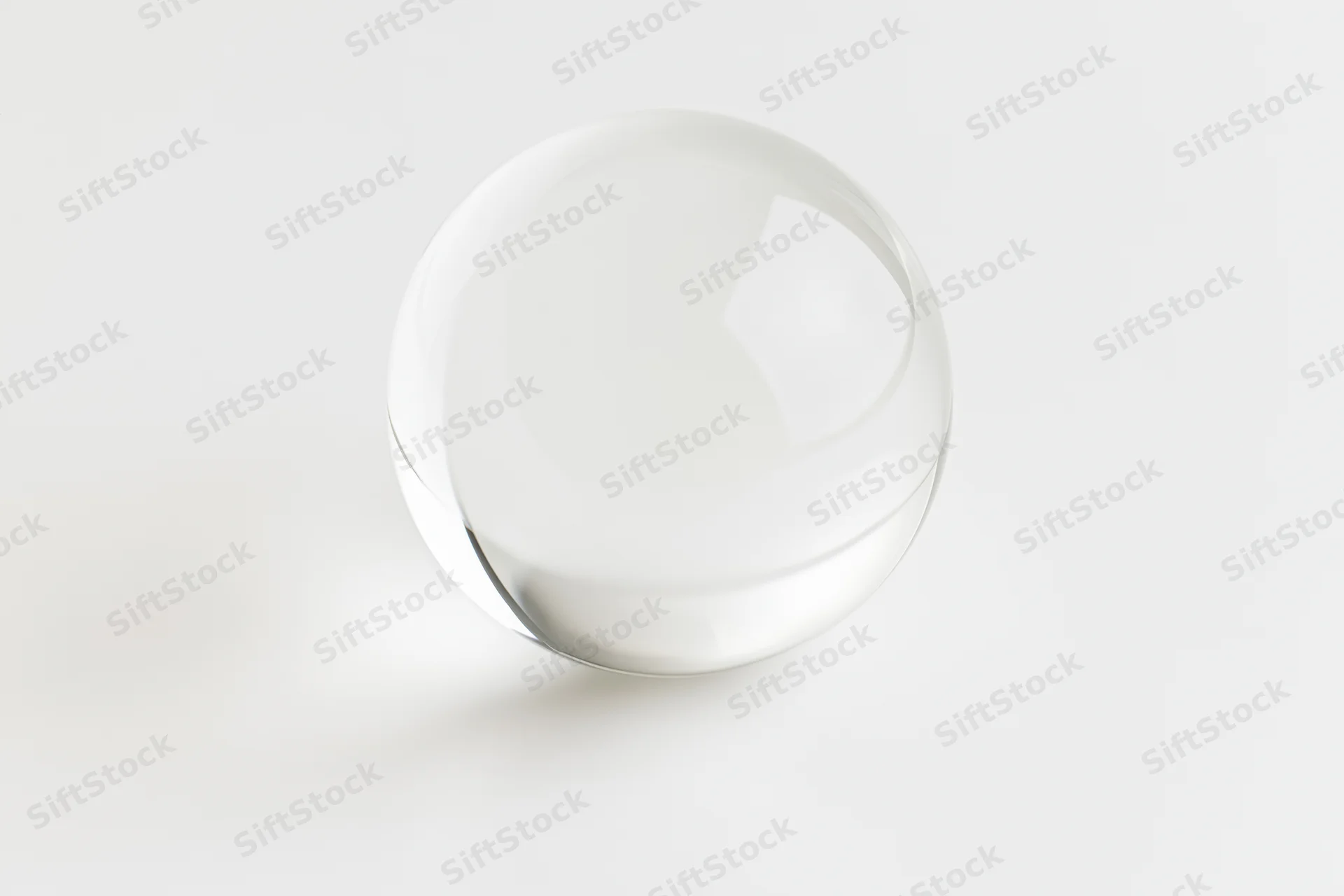 Clear glass sphere resting on plain white surface centered