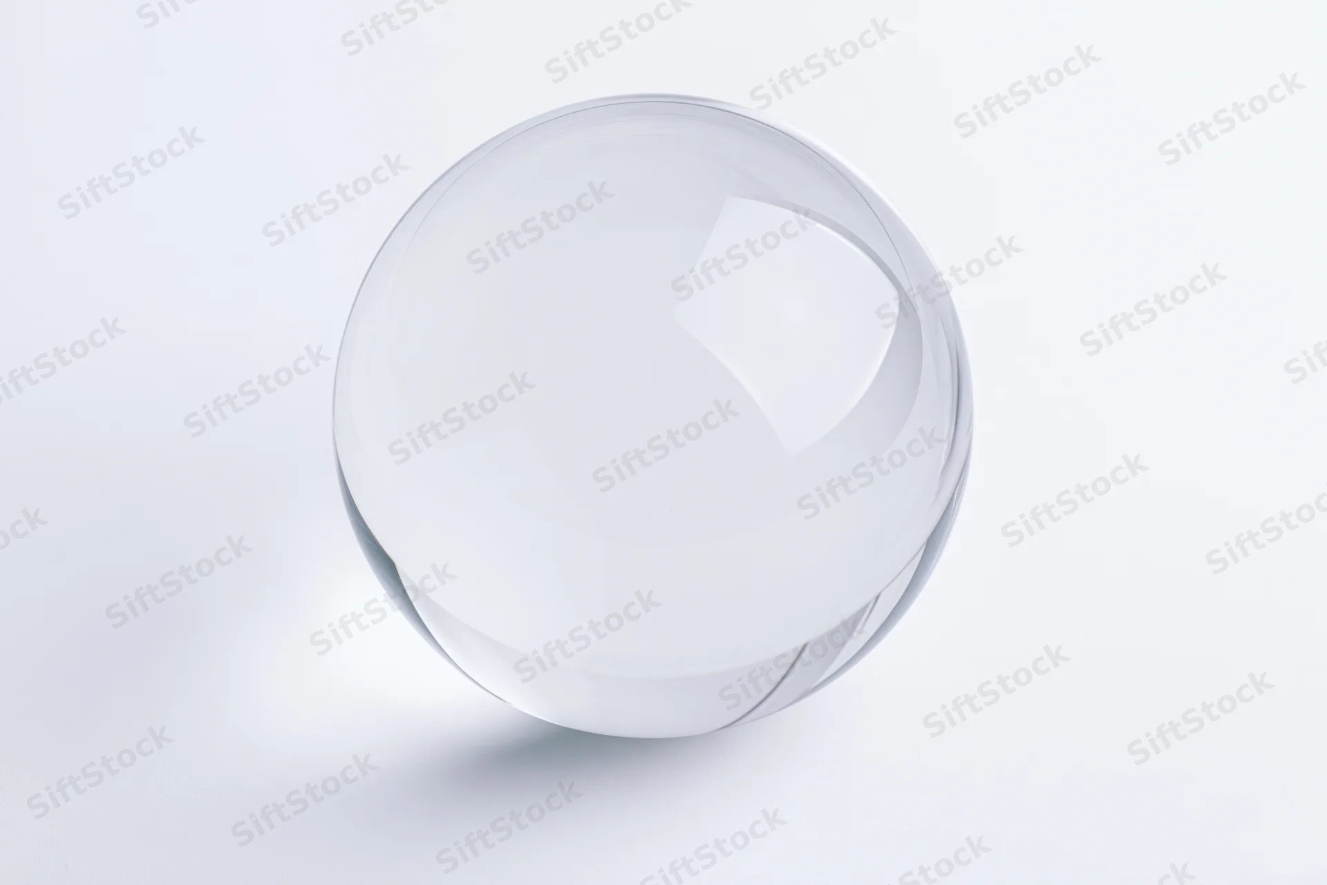 Clear glass sphere resting on plain white surface centered