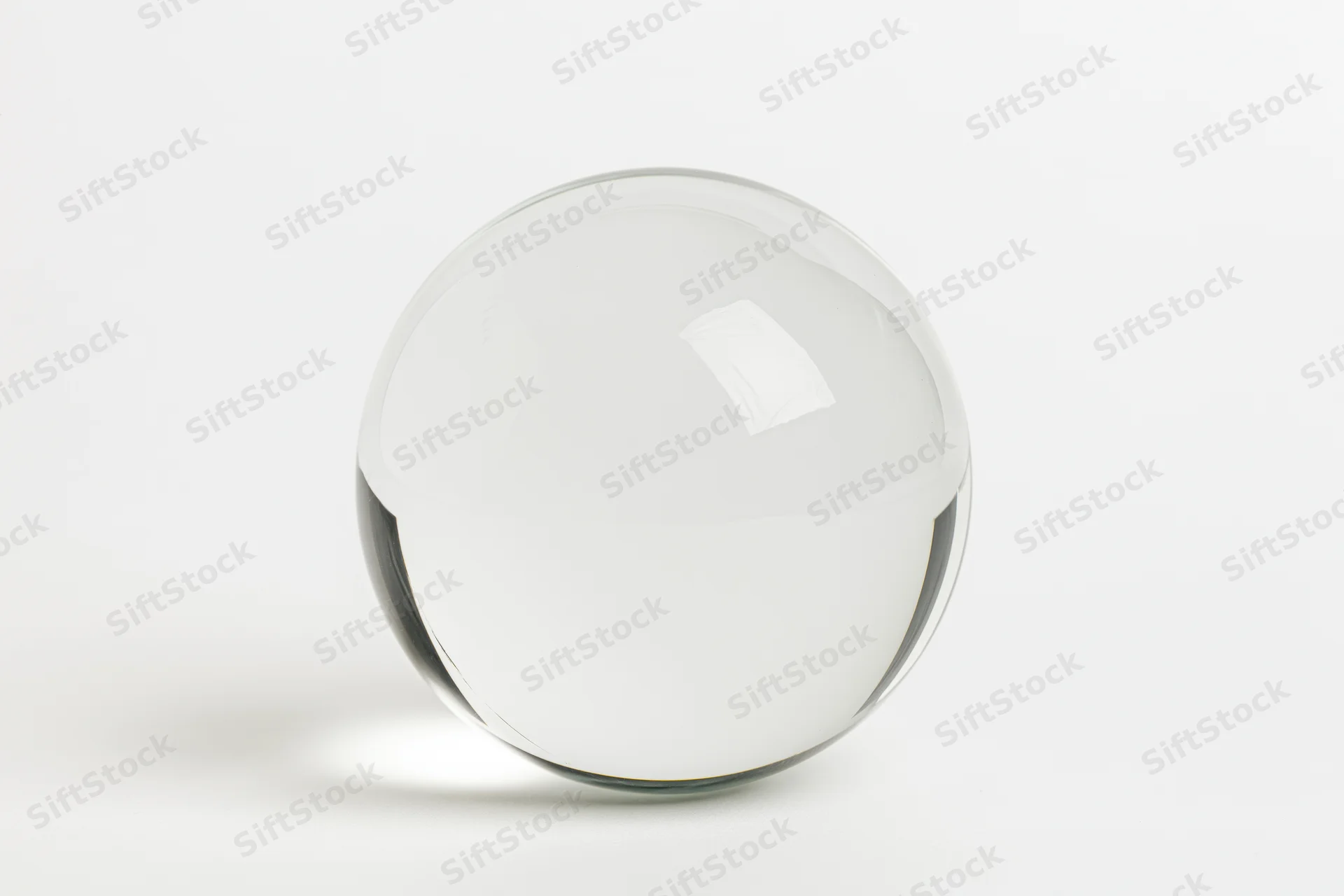 Clear glass sphere resting on a plain white surface centered