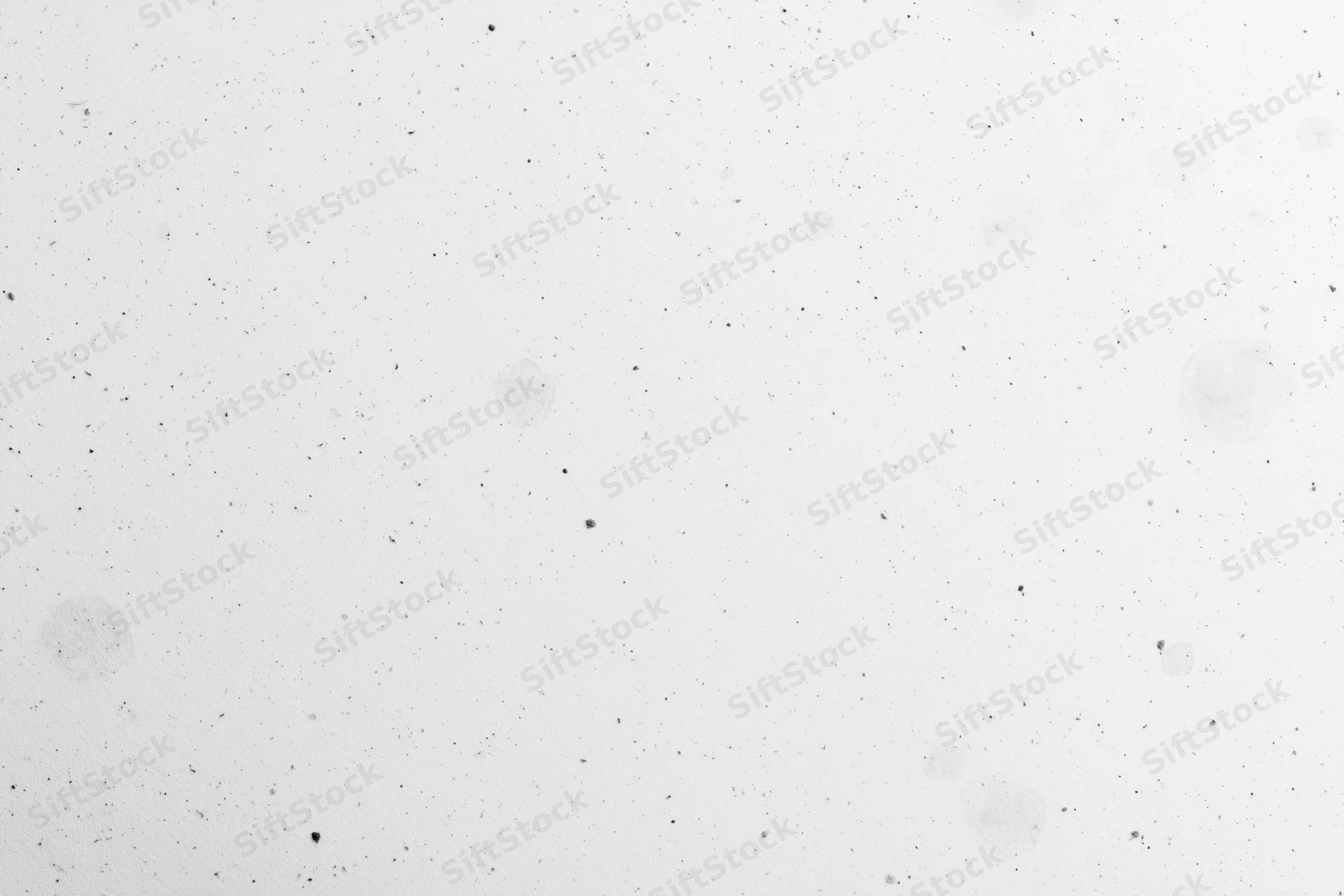 Close-up of a white paper surface with scattered speckles and faint stains, flat lay view