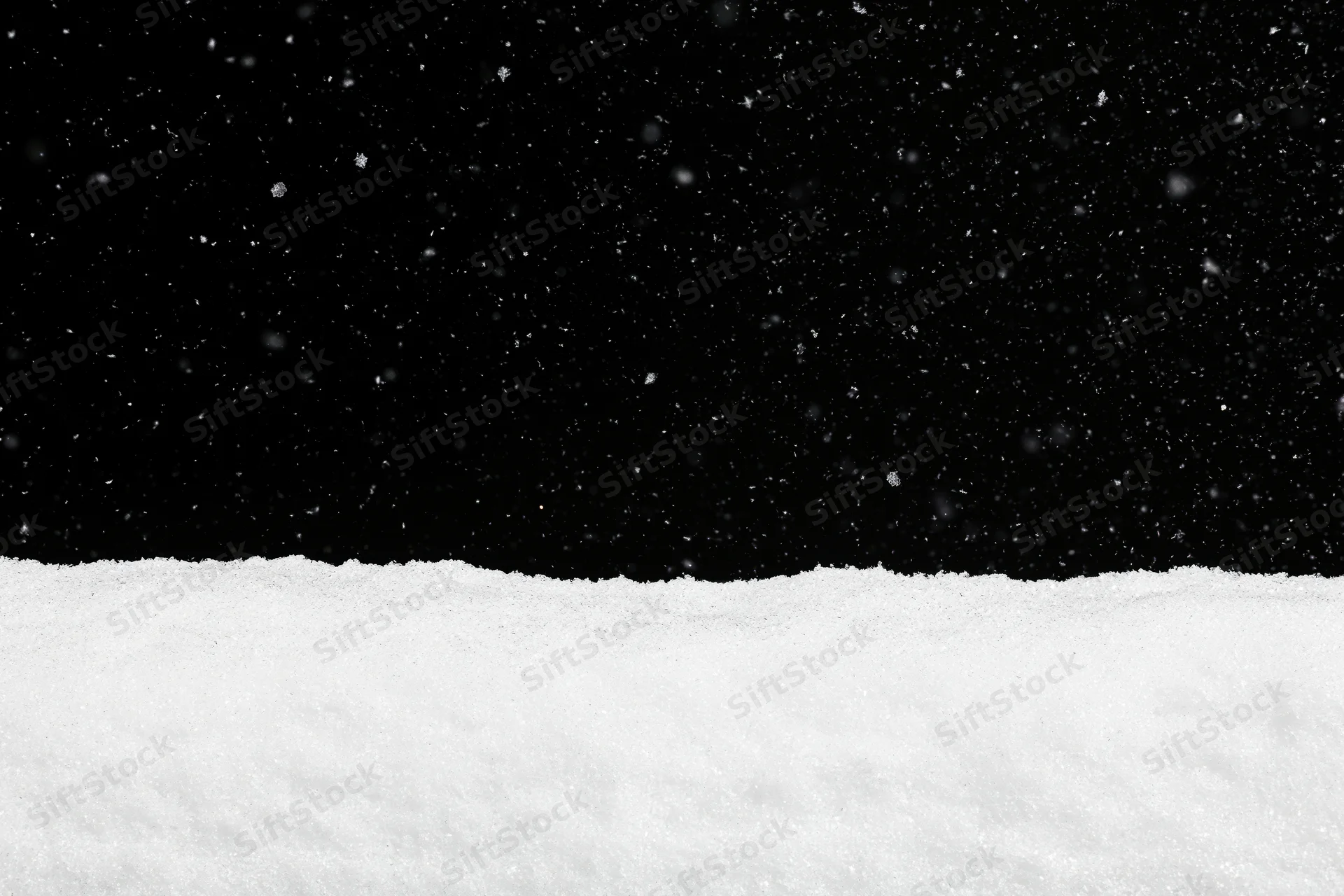 Close-up flat lay of snow surface against black background with falling snowflakes and copyspace