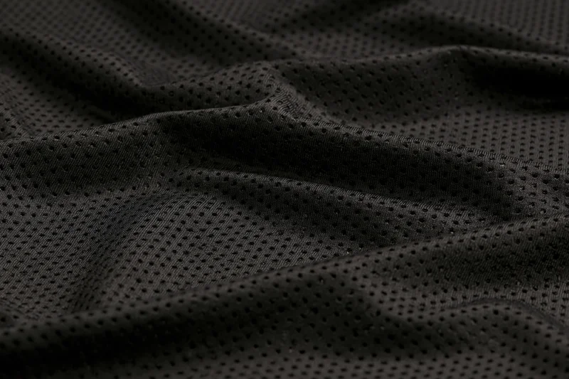 Close-up of black perforated athletic fabric with textured mesh pattern filling the frame
