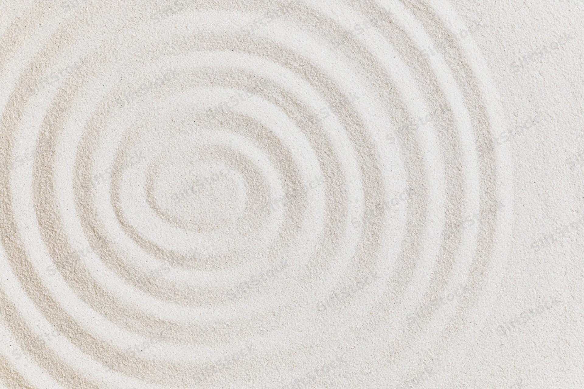 Raked white sand surface with concentric circles in a flat lay arrangement