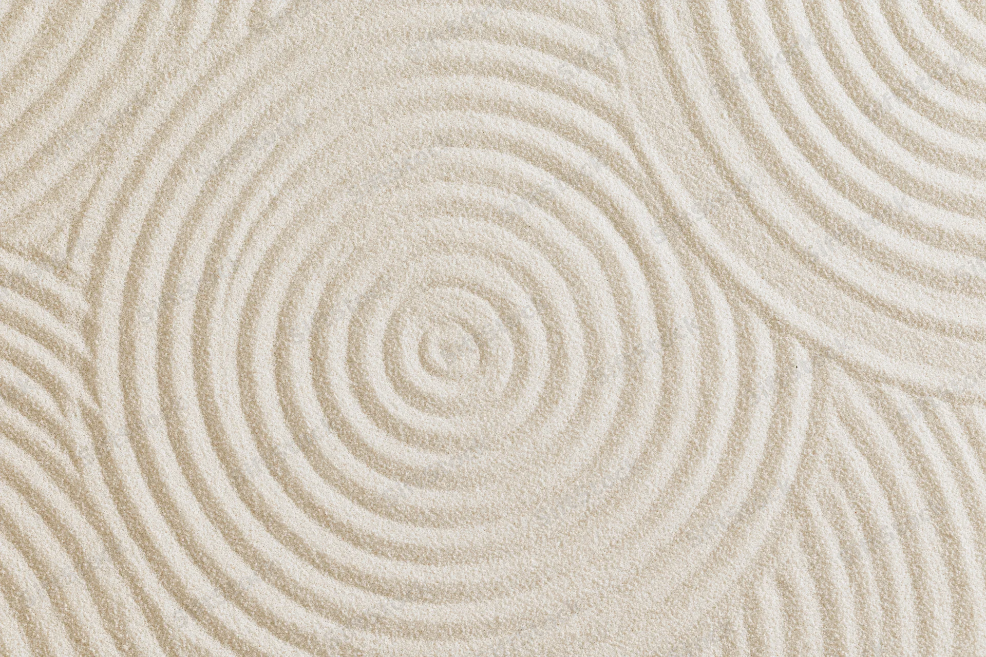 Raked white sand surface with concentric spiral patterns in a flat lay arrangement