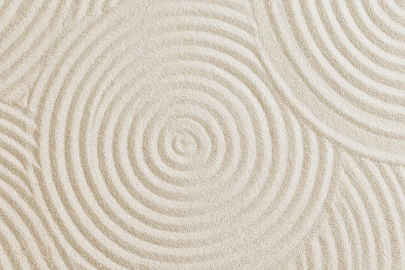 Raked white sand surface with concentric spiral patterns in a flat lay arrangement