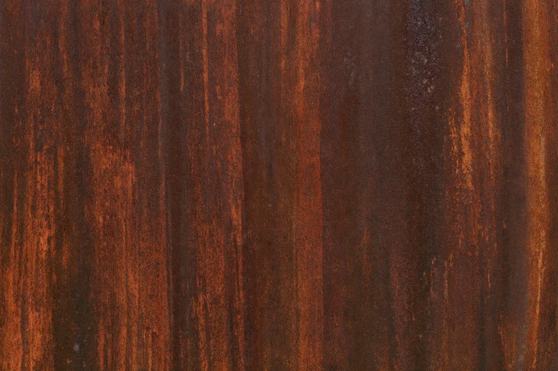 Close-up of heavily rusted metal surface with vertical striations and weathered texture