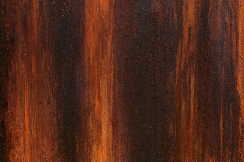 Close-up of heavily rusted metal surface with vertical streaks and textured patina