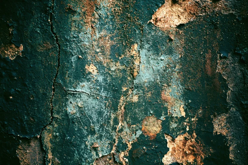 Close-up of a heavily weathered concrete surface with peeling paint and rusted patches