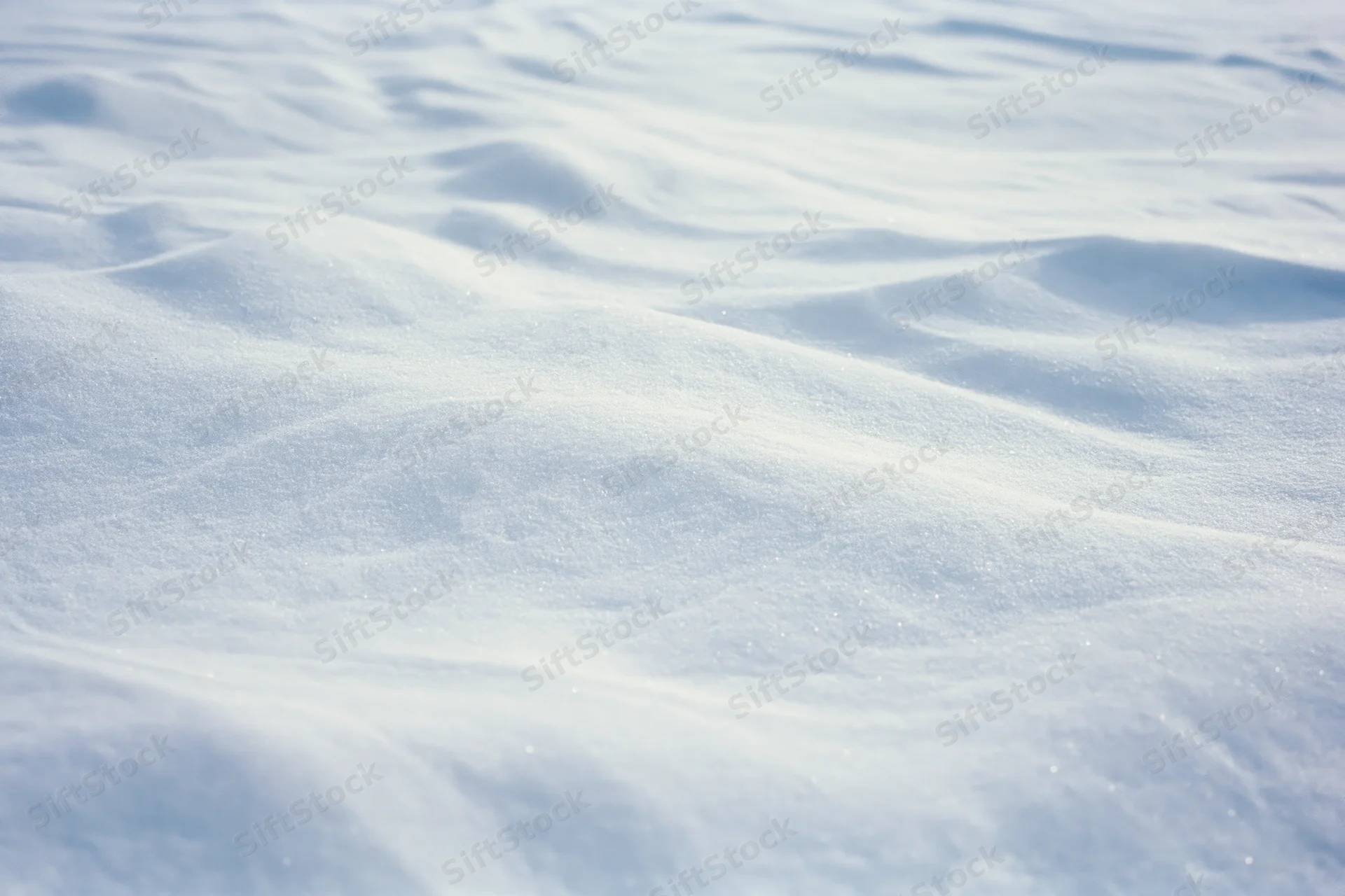 Closeup of undisturbed snow surface with soft ripples and sparkling texture under bright daylight