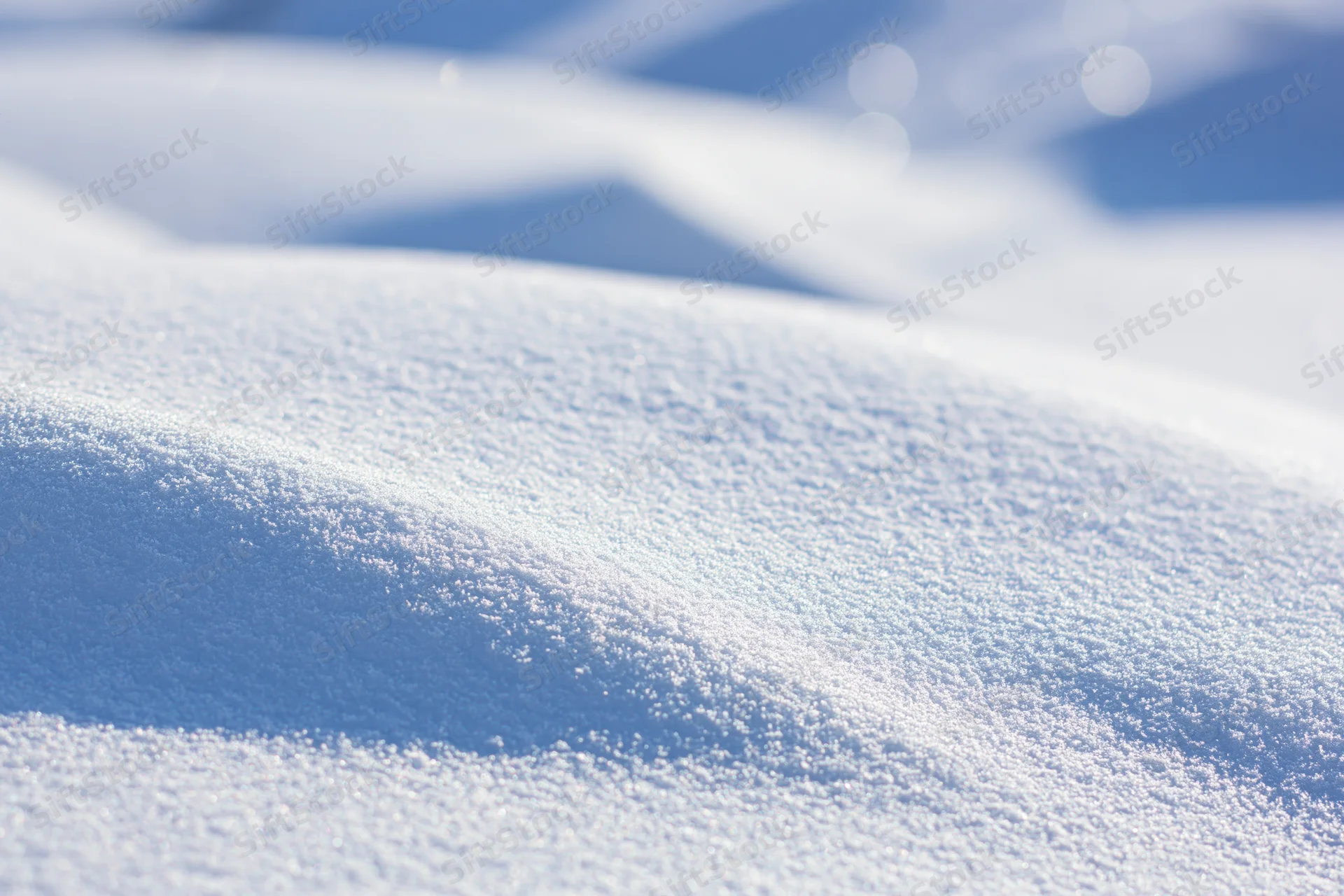 Close-up of smooth wind-sculpted snow drift on a sunlit ground surface