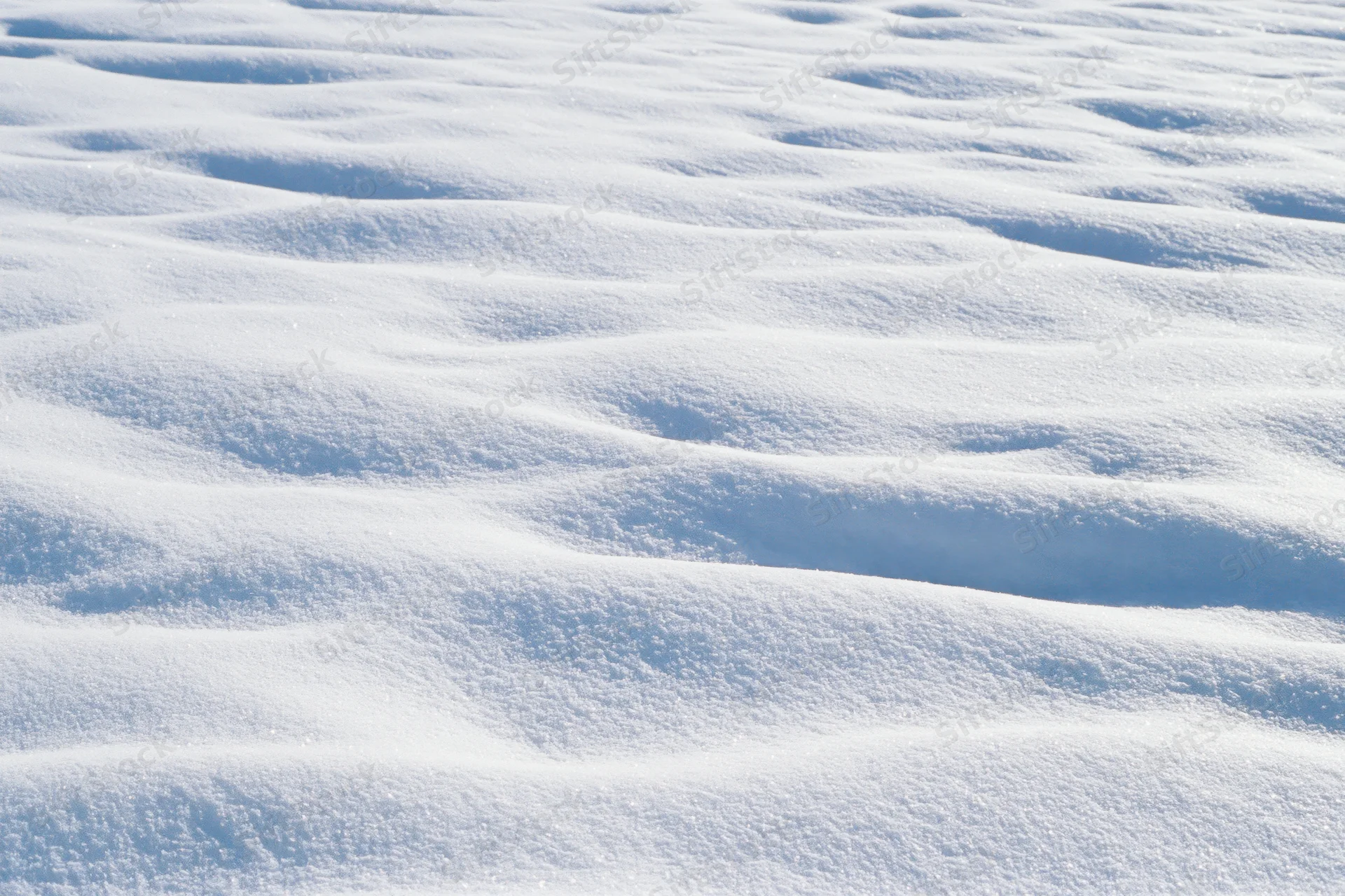 Close-up of undisturbed fresh snow surface with rippled texture under sunlight