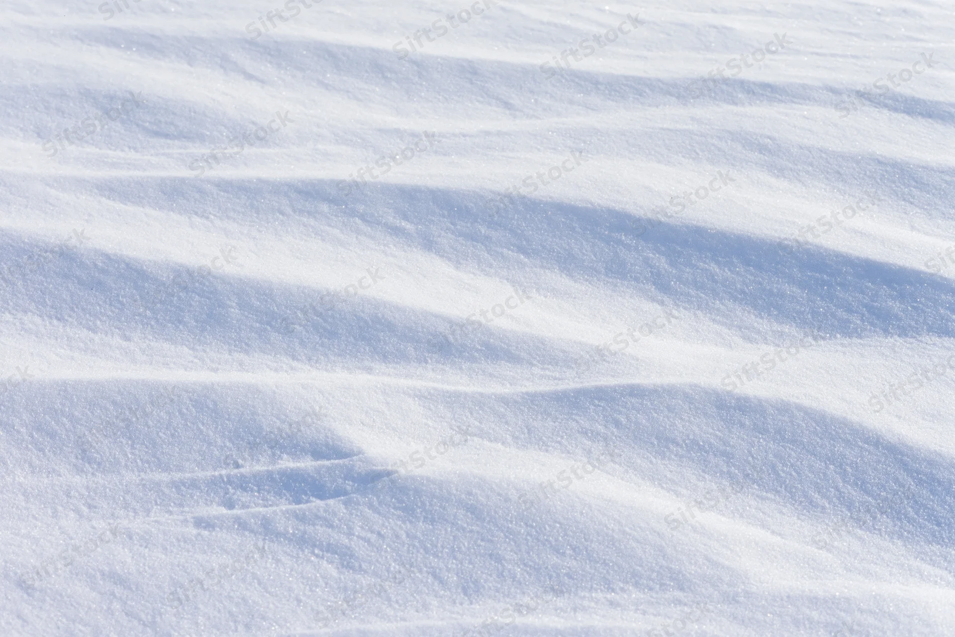 Closeup of undisturbed fresh snow surface with soft ridges and shadows