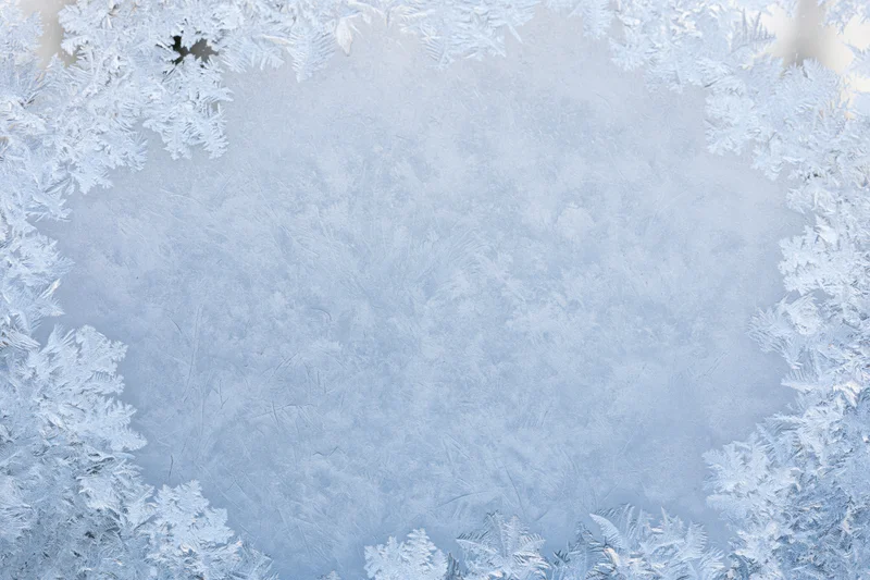 Frosted window pane with intricate ice patterns forming a border around a clear center