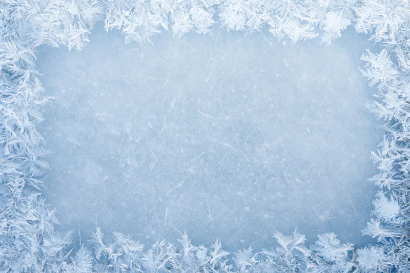 Frosted window pane with ice crystals forming a border around a clear center