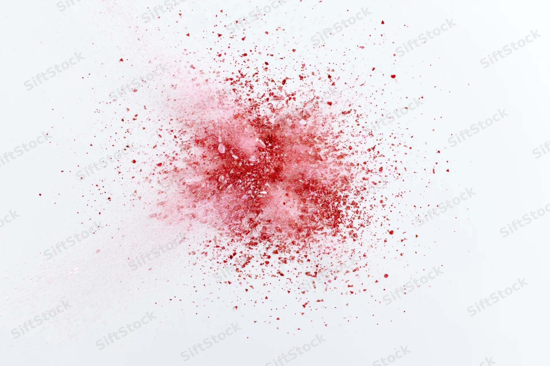 Red and pink powder burst in mid-air against white background