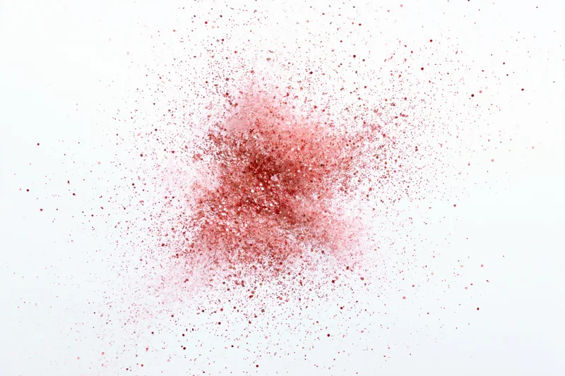Red powder bursting into fine particles against white background