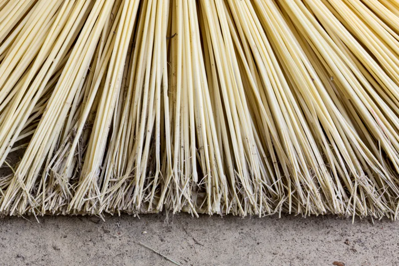 Close-up of worn broom bristles on a dirt surface