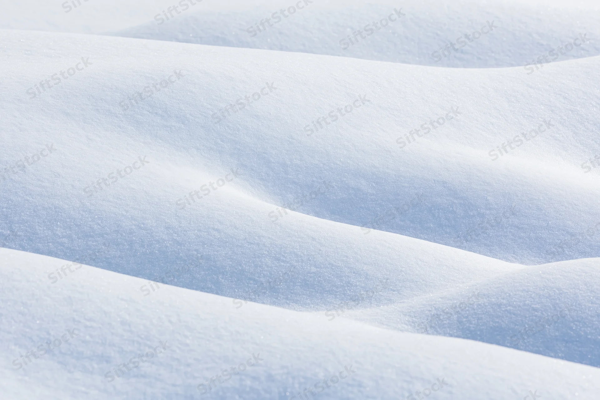 Undulating fresh snow drifts filling the frame in a close-up surface view