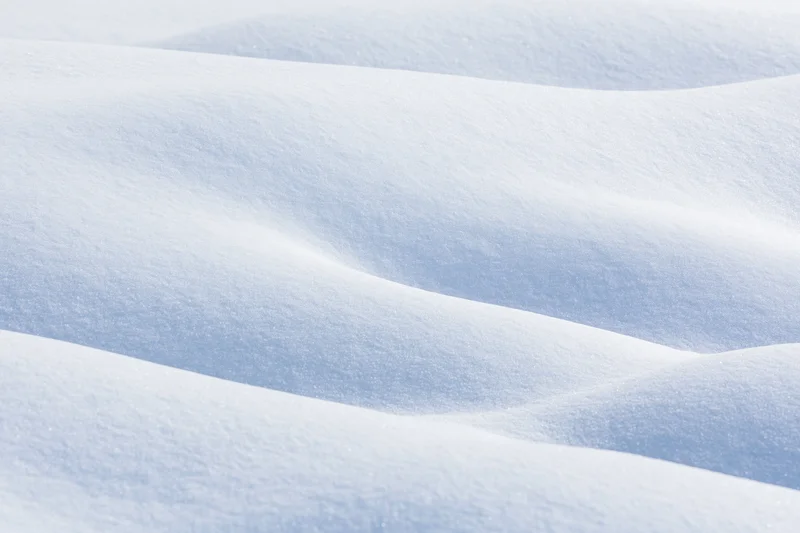 Undulating fresh snow drifts filling the frame in a close-up surface view