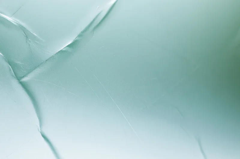 Close macro view of frosted translucent glass surface with subtle cracks and light reflections