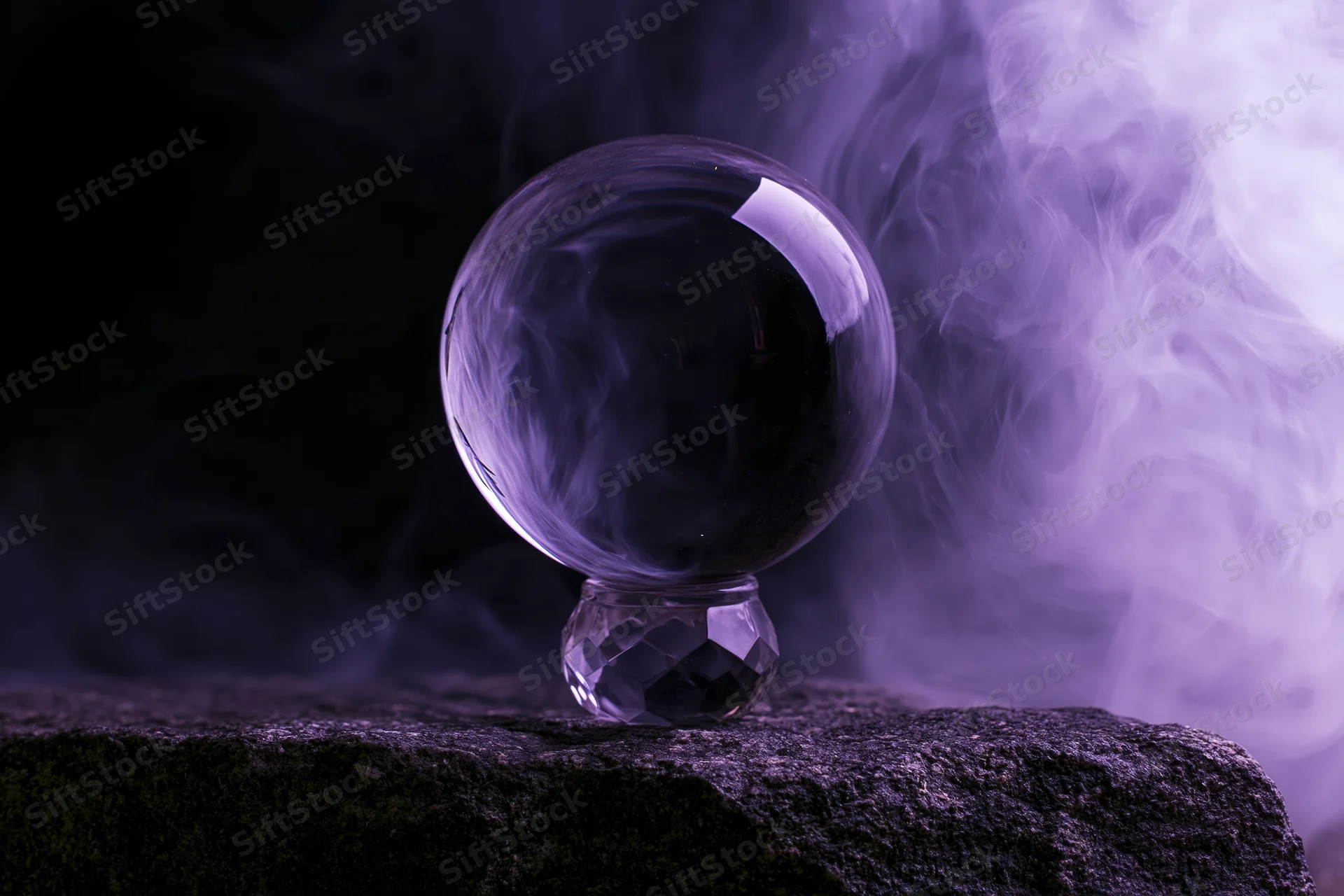Crystal ball on a faceted glass base resting on a dark stone with purple smoke swirling around it