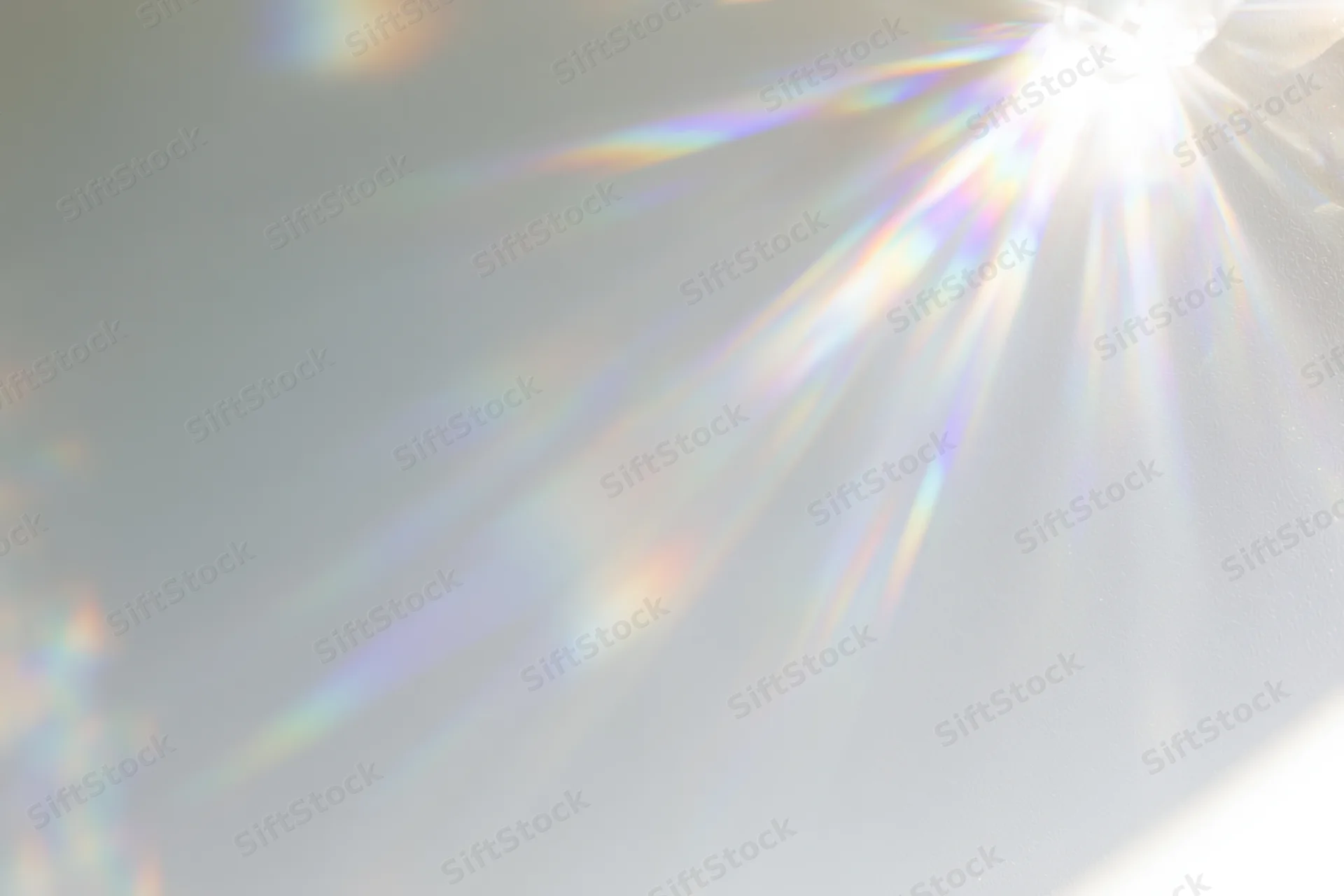 Light refraction pattern with rainbow spectrum cast across a plain matte white surface