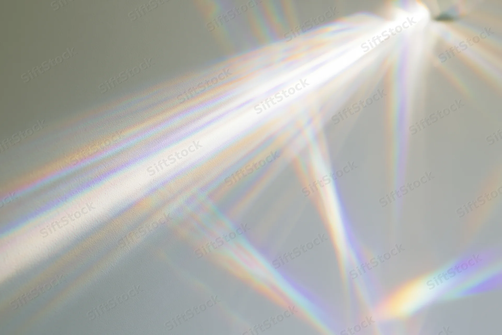 Light refraction pattern cast across a plain matte surface with rainbow spectrum and geometric beams