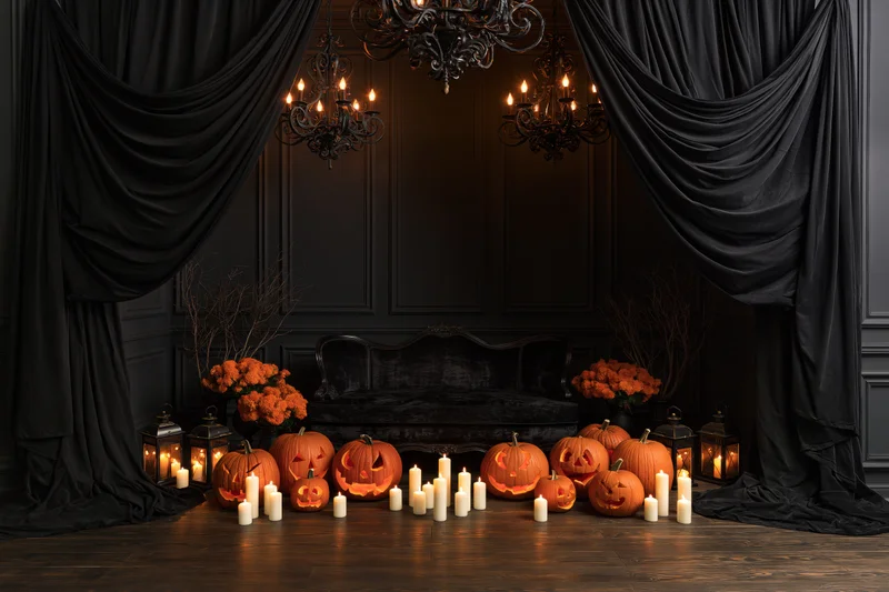 Carved pumpkins and candles arranged in a dark victorian room with black drapes and chandeliers