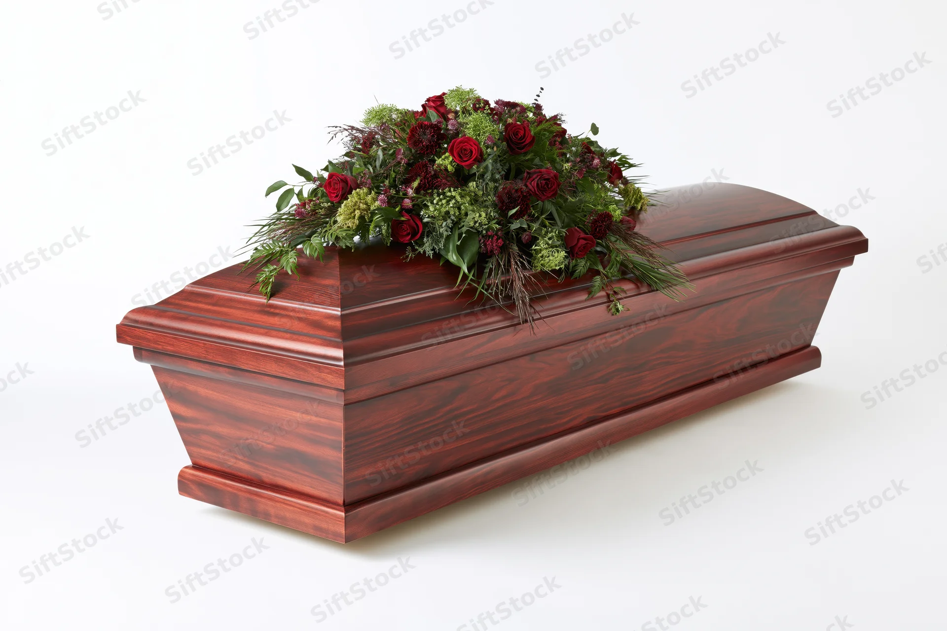 Dark mahogany wooden coffin with floral arrangement on white background