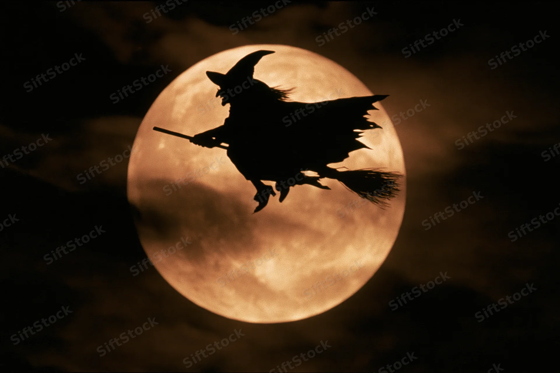Witch flying on broomstick silhouetted against full moon in night sky