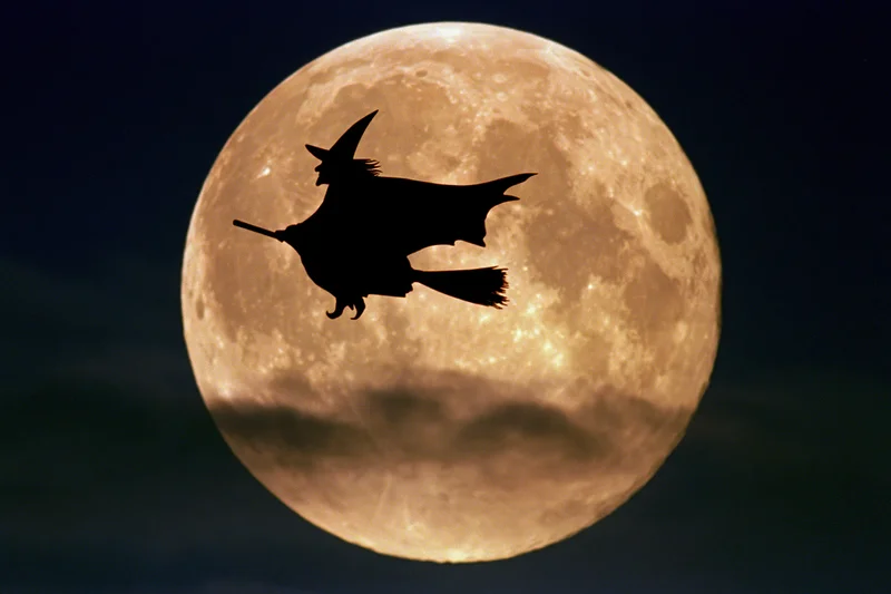 Witch flying on broomstick silhouetted against full moon in night sky