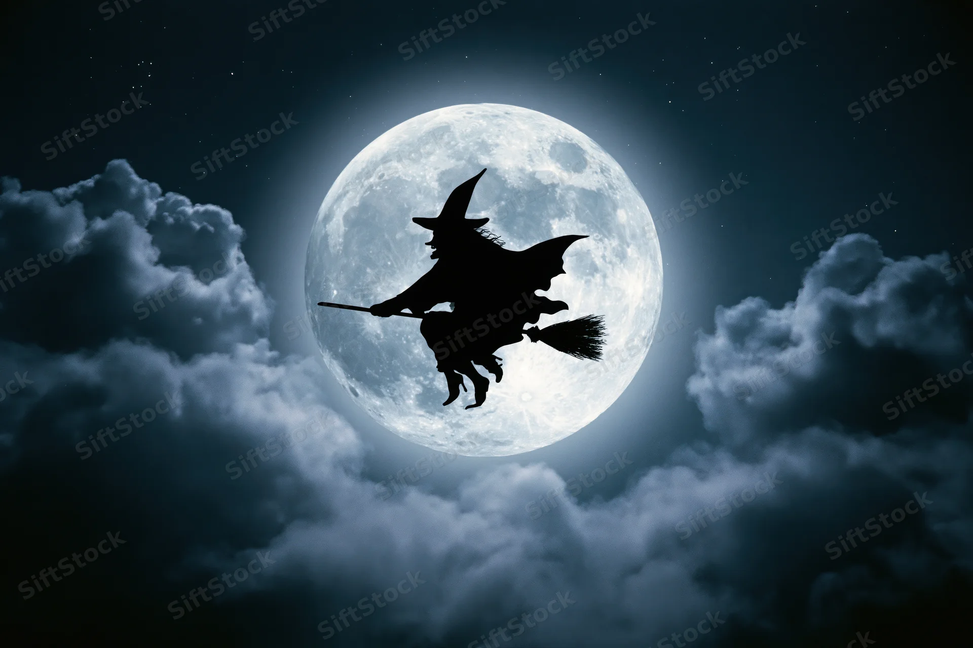 Witch flying on broomstick silhouetted against full moon in cloudy night sky