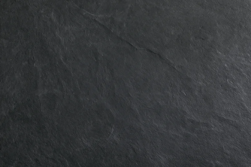 Dark slate stone surface with natural texture and veining filling the frame