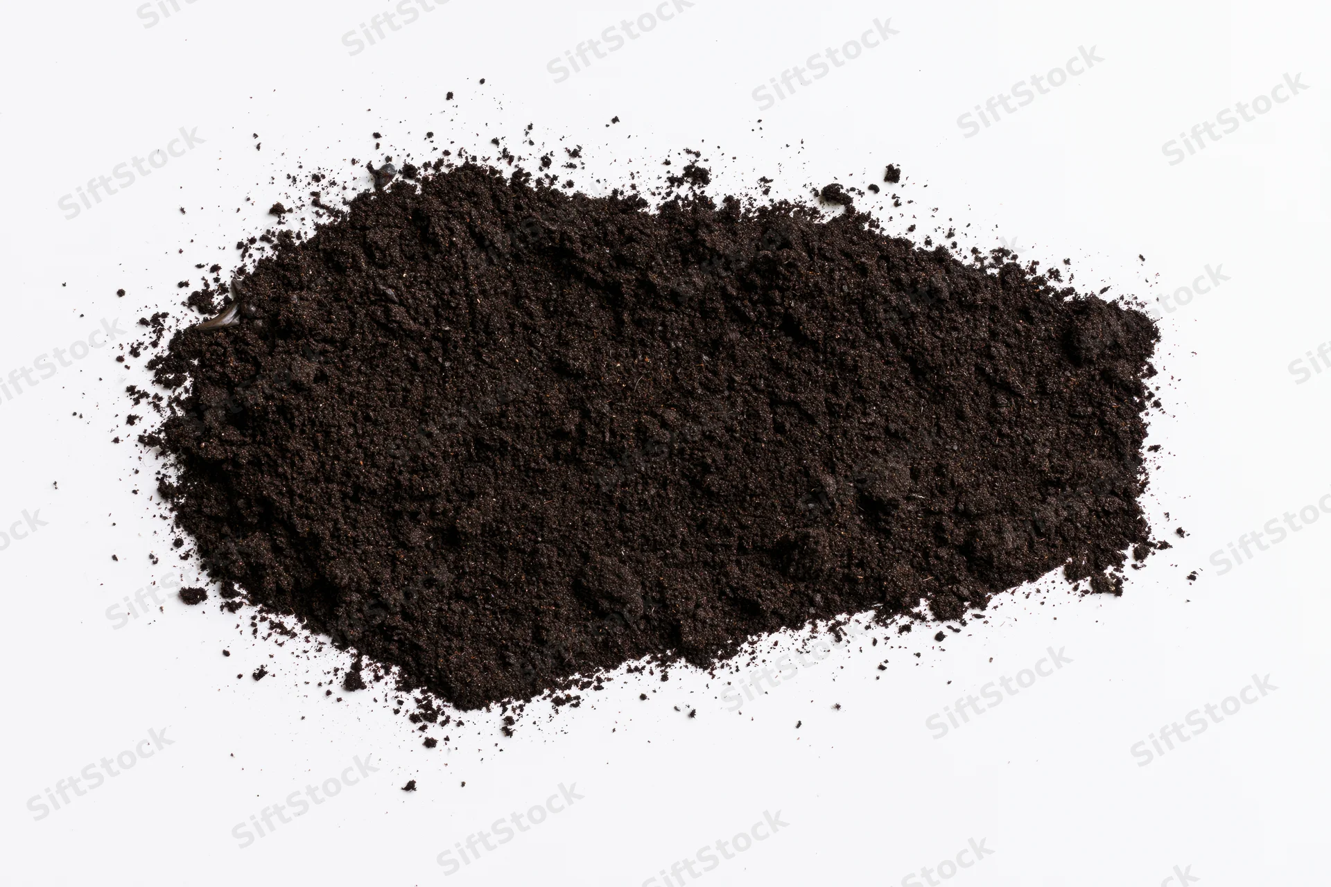 Dark soil scattered on a plain white surface forming a mound