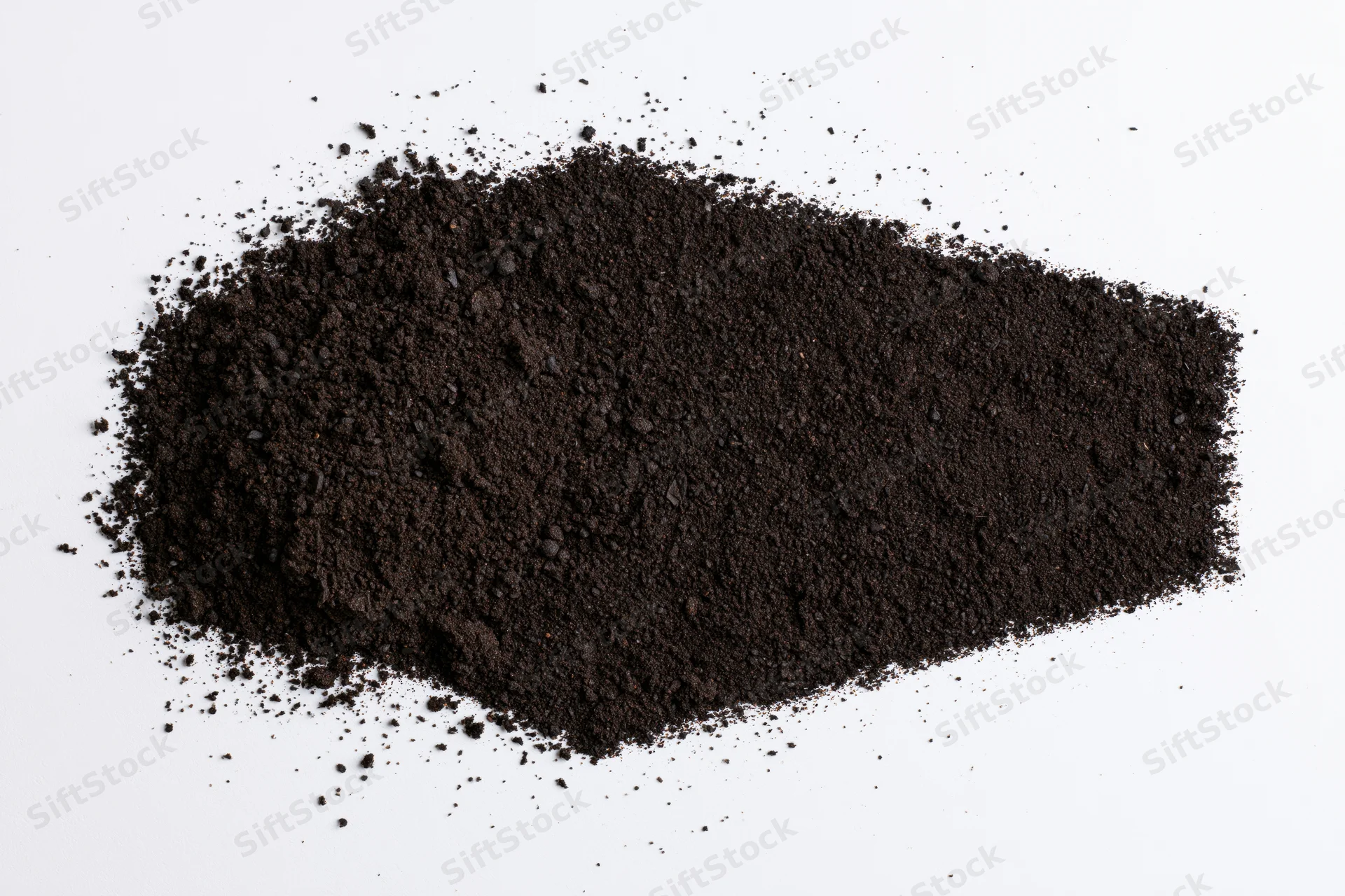 Dark soil piled and scattered on a white surface