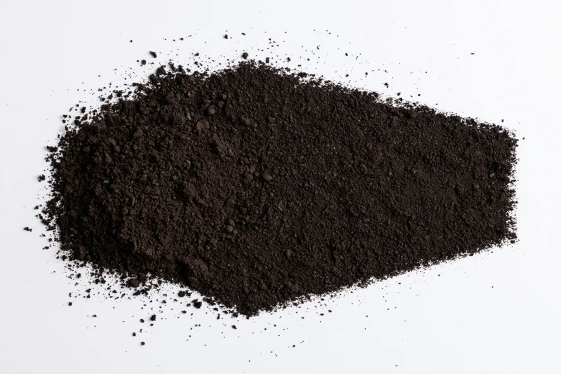Dark soil piled and scattered on a white surface