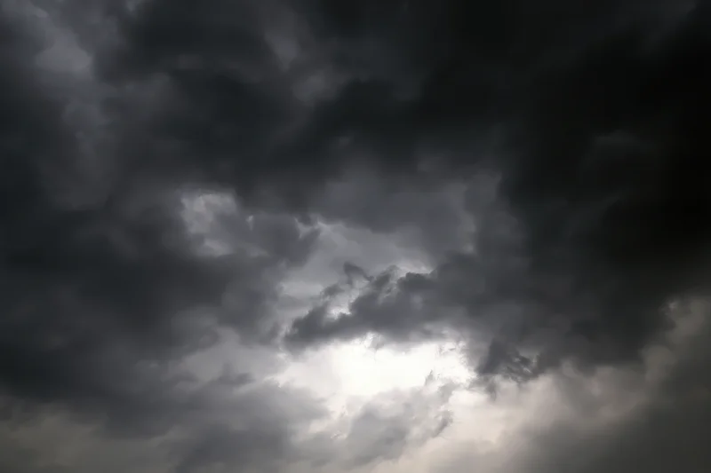Dark storm clouds filling the sky with sunlight breaking through