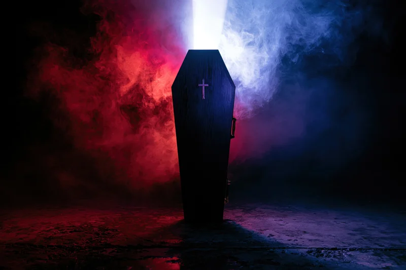 Dark wooden coffin with silver cross standing upright in smoky room lit by red and blue beams