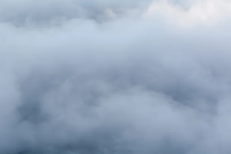 Billowing steam and mist spreading across a flat surface in an overcast outdoor scene