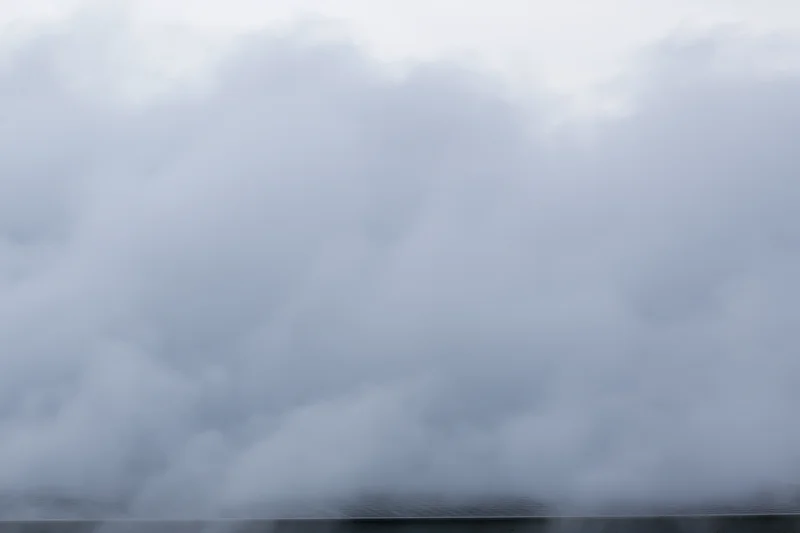 Dense white steam billowing across a flat surface under an overcast sky