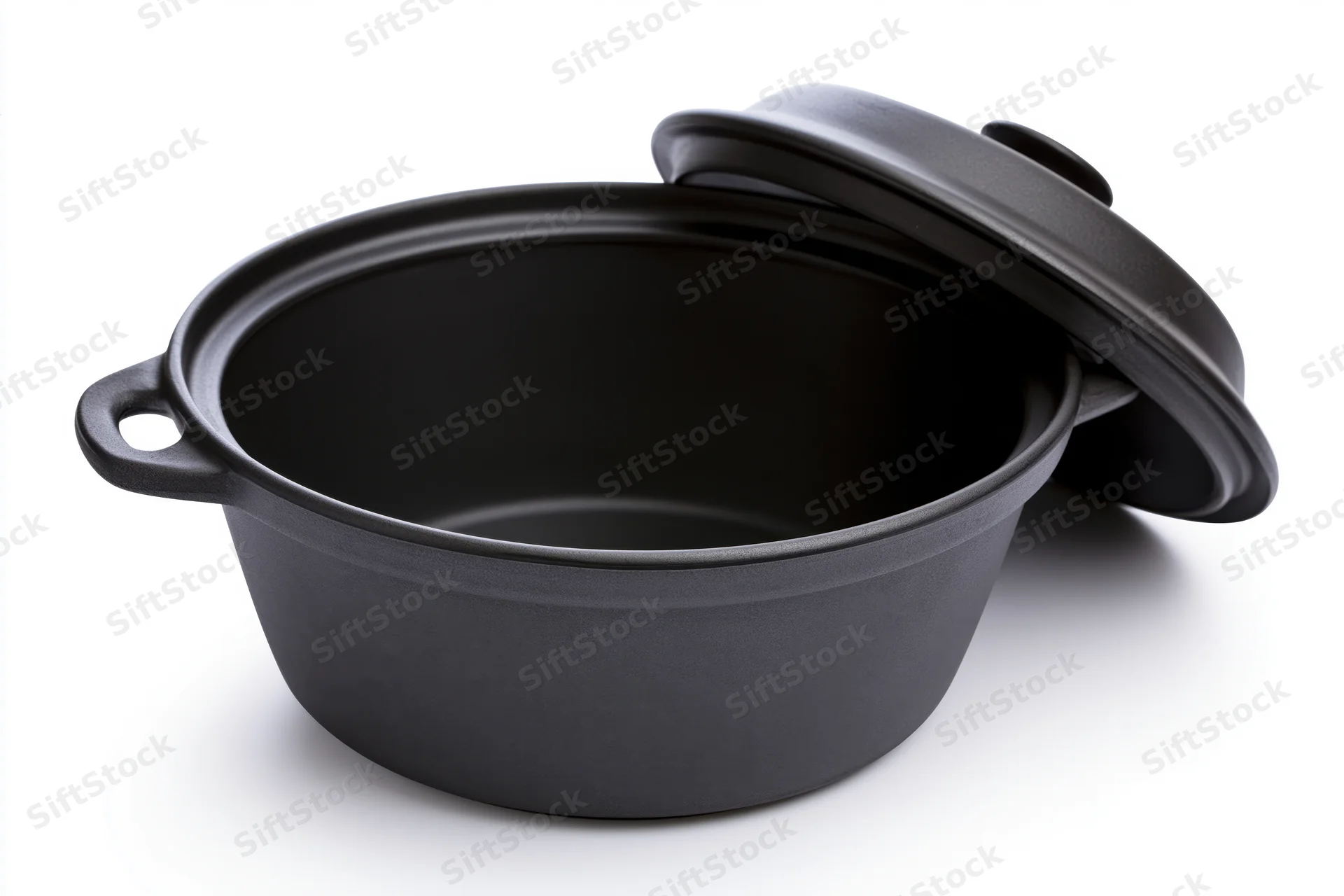 Black ceramic cooking pot with lid resting against it on white background