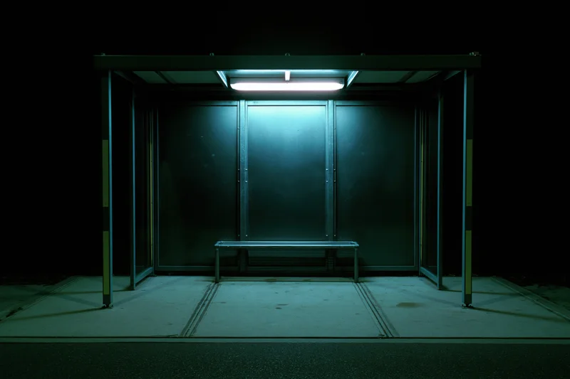 Empty bus shelter illuminated by a single fluorescent light at night