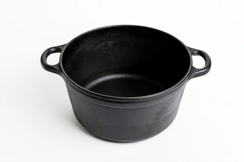 Empty cast iron dutch oven with two loop handles on white background