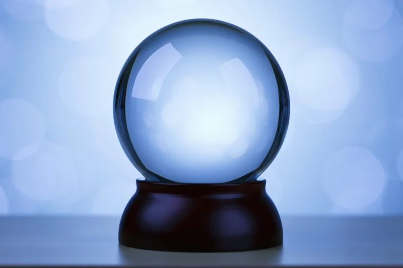 Clear glass crystal globe on dark wooden base against soft blue bokeh background
