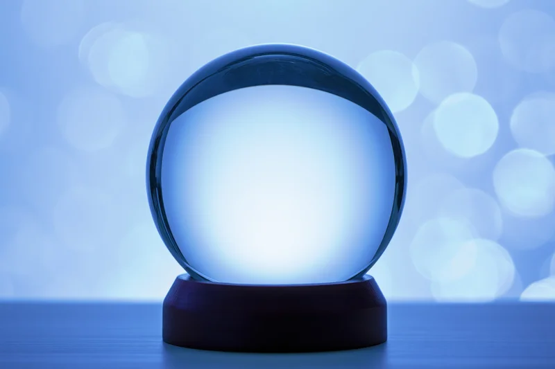 Glowing crystal sphere on a dark wooden base against a blue bokeh background