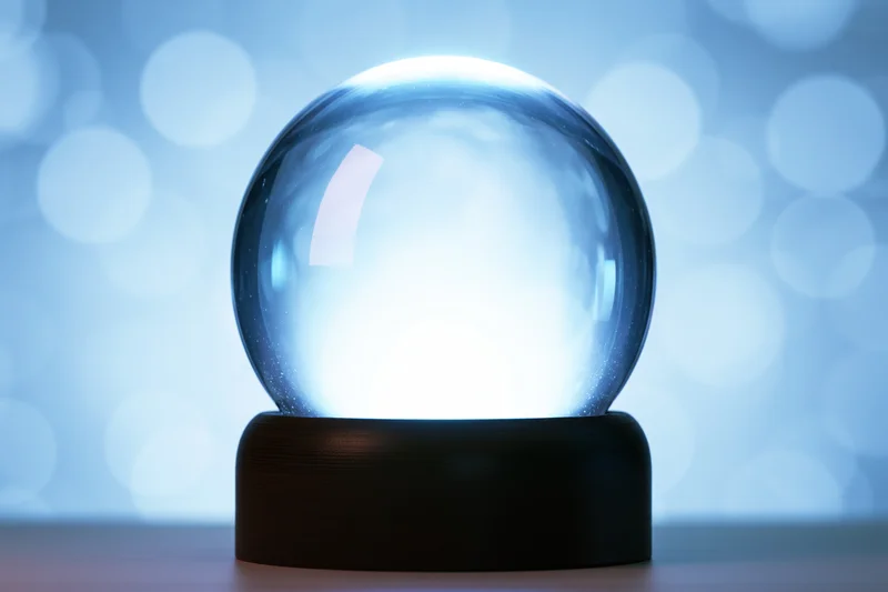 Illuminated glass globe on dark wooden base against blue bokeh background