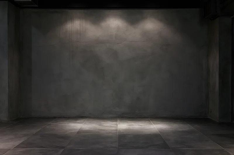 Empty industrial room with bare concrete walls and tiled floor under spotlight lighting