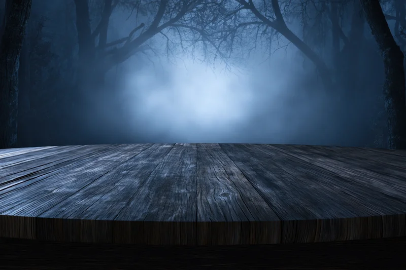 Weathered wooden plank table in a misty dark forest at night